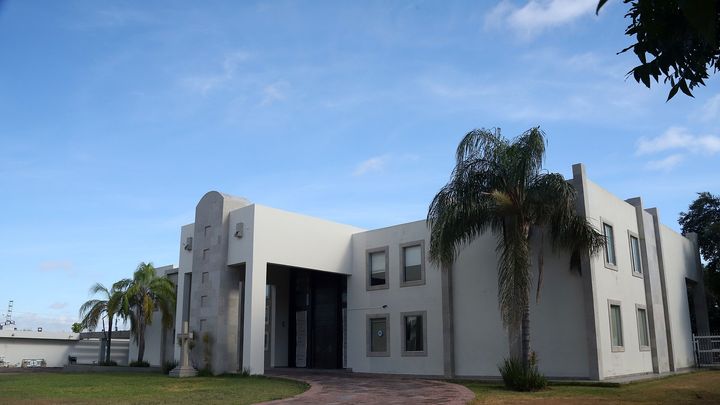 Entrada principal del campus del Instituto Newman en Reynosa, con cruz y palmeras