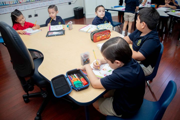 Estudiantes trabajando en sus pupitres en el aula