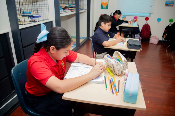 Alumna escribiendo durante una actividad en clase